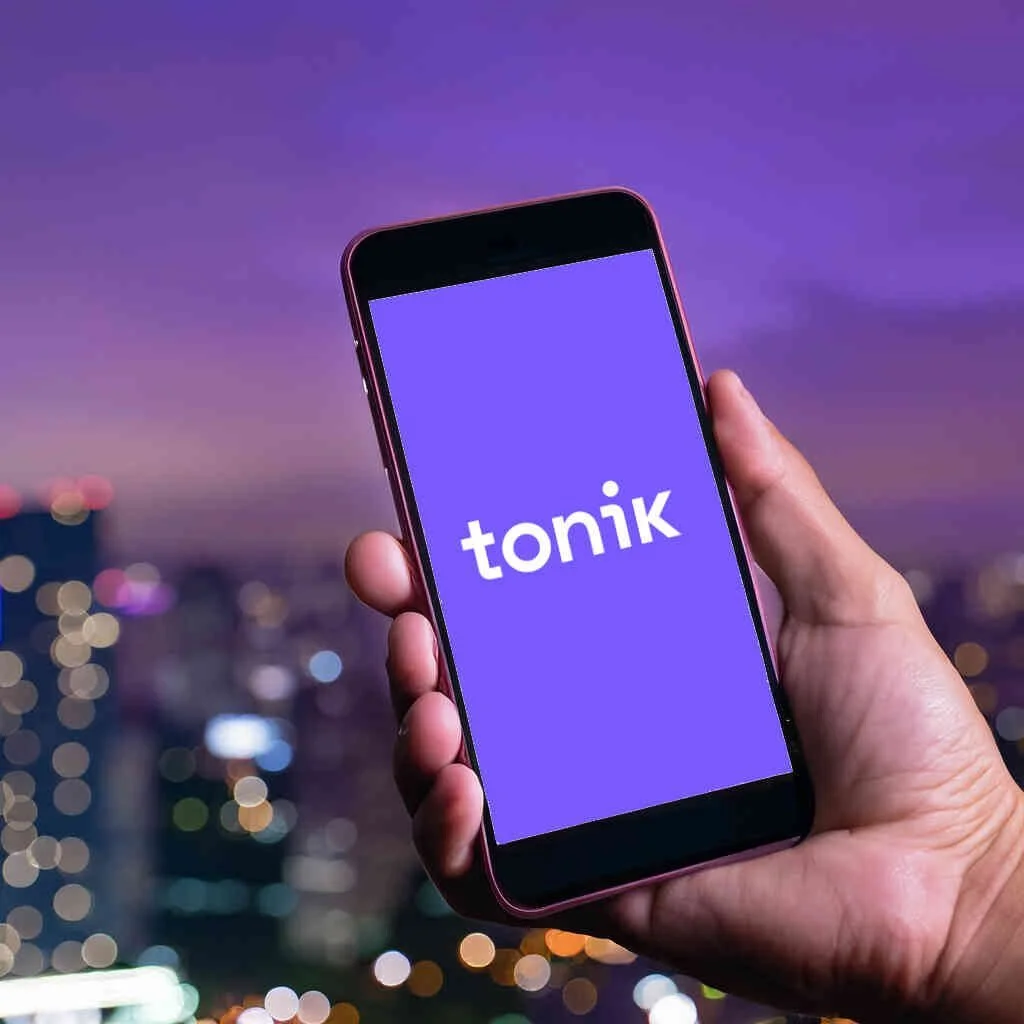 Hand holding a phone displaying Tonik logo
