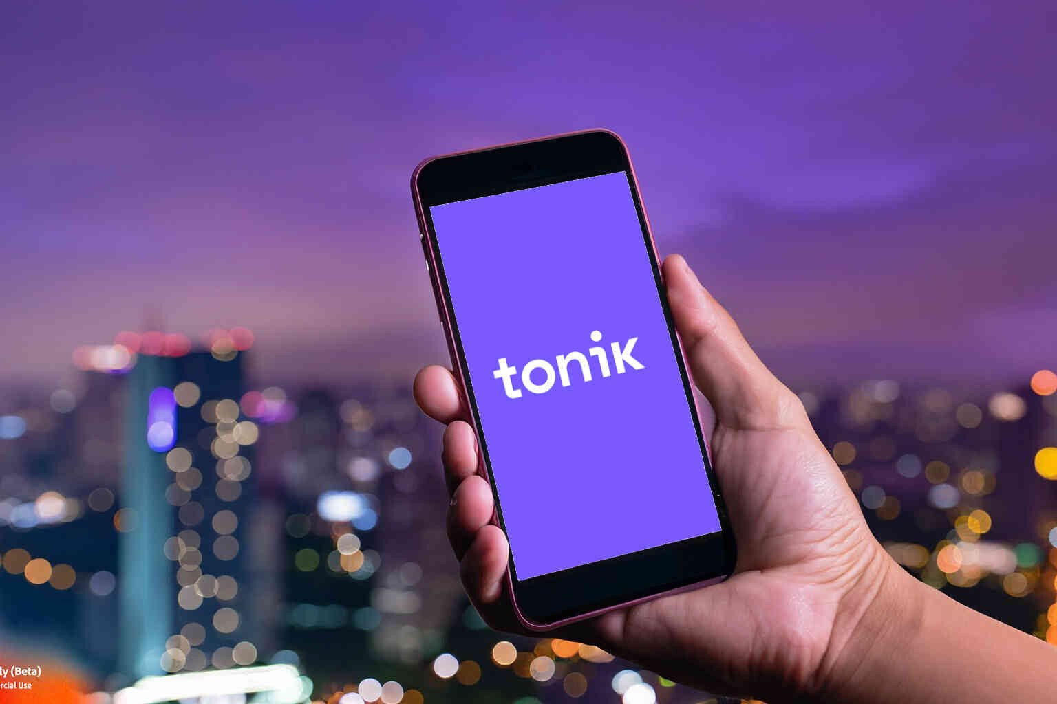 Hand holding a phone displaying Tonik logo